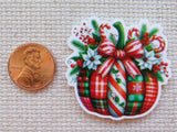 Christmas-themed candy and bow design minder next to a penny on a textured surface
