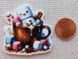 Minder of a snowman in a hot chocolate mug with marshmallows and candy, next to a penny for scale.