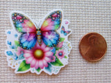 Colorful butterfly and flower minder next to a penny on a textured surface