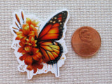 Minder of a butterfly and flowers next to a penny on a textured surface