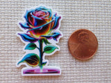 Colorful rose-shaped minder next to a penny on a textured surface