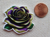 Rose-shaped minder next to a penny on a textured surface
