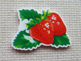 Minder of a strawberry with green leaves on a textured beige background