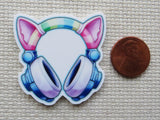 Minder of cat ears with headphones on a textured surface next to a penny for scale.