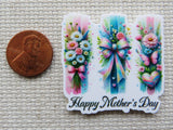 Minder with floral designs and 'Happy Mother's Day' text next to a penny for size comparison on a textured surface.