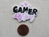 Minder with 'Gamer Girl' text on a textured surface next to a penny for scale.