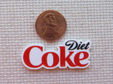 Diet Coke logo minder next to a penny on a textured background.