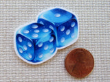 Blue dice with white dots minder next to a penny on a textured surface