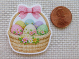 Minder of a woven basket with Easter eggs and a pink bow, next to a penny for scale.