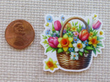 Minder of a floral basket with tulips and daisies next to a penny for scale on a textured surface.