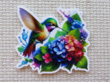 Colorful minder of a hummingbird and flowers on a textured beige background