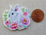Minder of a rabbit surrounded by flowers next to a penny on a textured surface