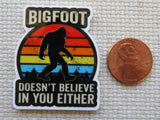 Minder with Bigfoot design next to a penny on a textured surface