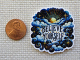 Decorative minder with 'Believe in Yourself' text next to a penny on a textured surface