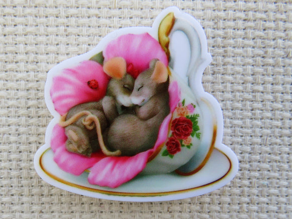 First view of pair of mice are sleeping in a teacup with a pink flower minder.