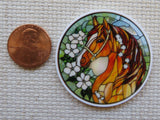 Stained glass-style horse minder next to a penny on a textured surface