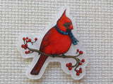 A minder featuring a red cardinal bird wearing a blue plaid scarf, perched on a branch with red berries, displayed on a textured beige fabric background.