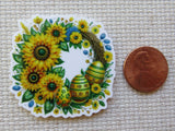 Minder with sunflowers and patterned eggs next to a penny for scale on a textured surface.