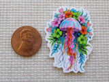 Colorful jellyfish minder with flowers next to a penny on a textured fabric background
