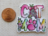 Colorful 'CAT MOM' minder with a penny for scale on a textured surface