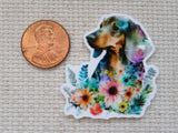 Colorful dog minder with floral design next to a penny on a textured surface