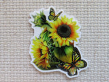 A minder featuring a vibrant sunflower and butterfly design, displayed on a textured beige fabric background.