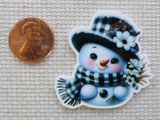 Second view of Black and white snowman with a checkered hat and scarf with white daisy flowers minder.