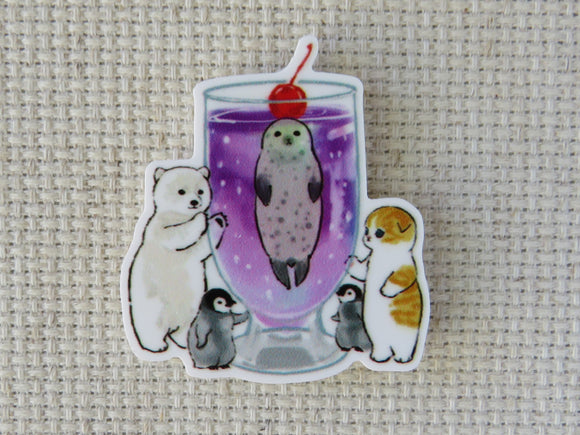 First view of a seal in a purple drink with a polar bear, orange cat, and a couple of penguins looking in needle minder.
