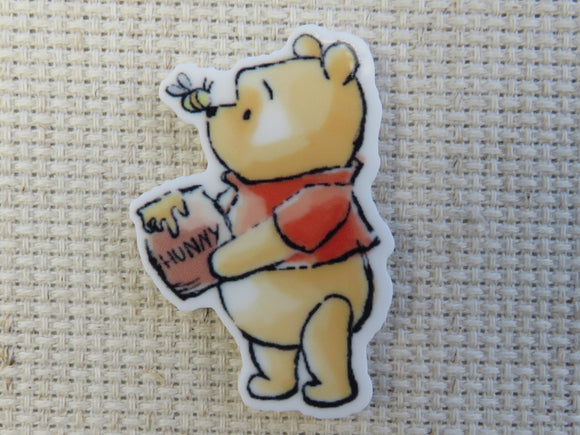 First view of Pooh Bear is holding a pot of honey and has a bee sitting on his nose minder.