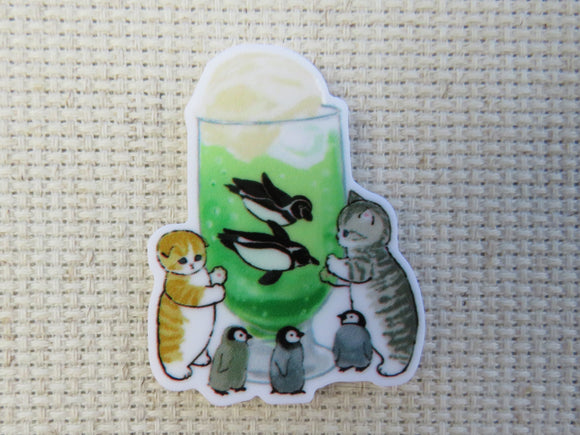 First view of A couple of tabby cats and baby penguins are watching mom and dad penguin swim inside a frothy green drink minder.
