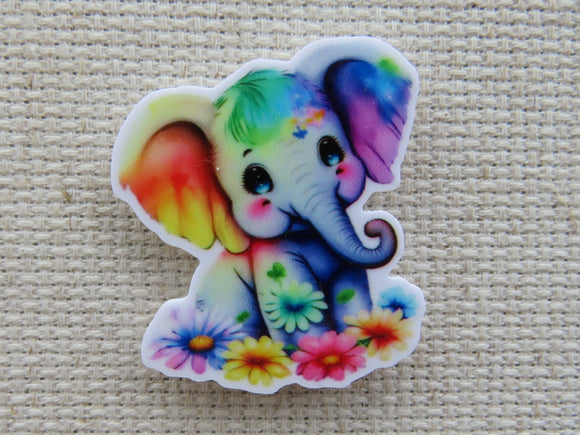 First view of an adorable elephant looks like someone splashed him with all of the colors of the rainbow and then laid flowers at his feet minder.