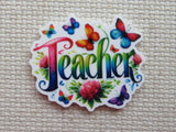First view of the word "teacher" in a rainbow of colors with colorful butterflies around minder.