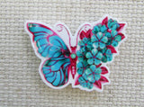 First view of half blue butterfly and half blue flowers needle minder.