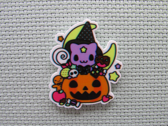 First view of the Purple Cat Wearing a Witch's Hat in a Carved Pumpkin full of Candy in Front of a Moon Needle Minder